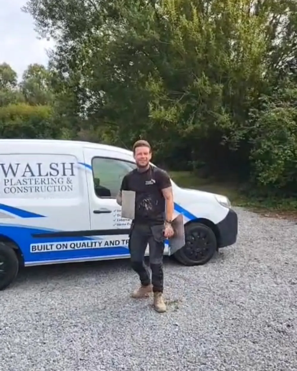 One of the crew beside the small van on a gravel drive
