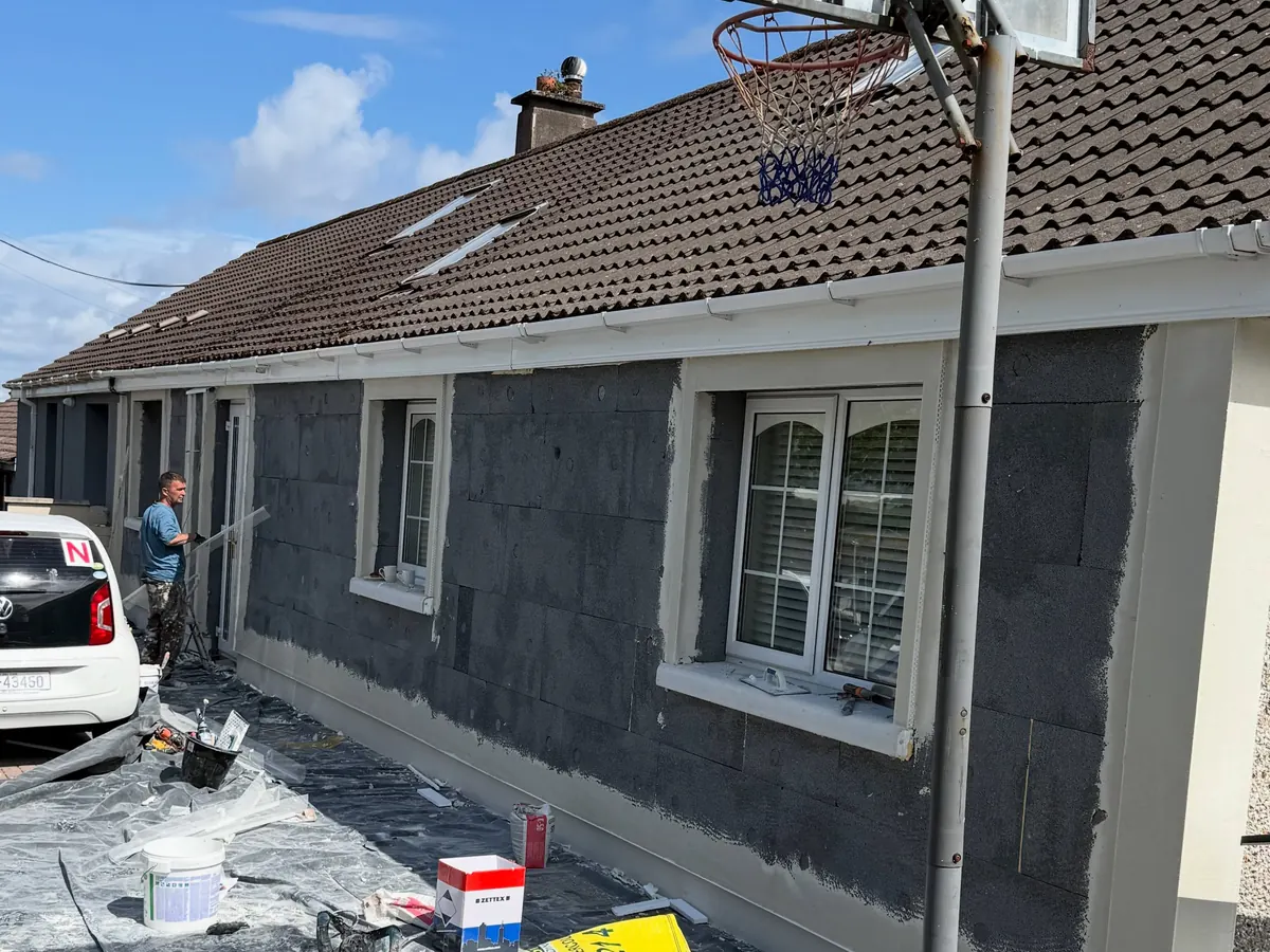 The front of a bungalow with grey insulation boards fixed and materials on the drive