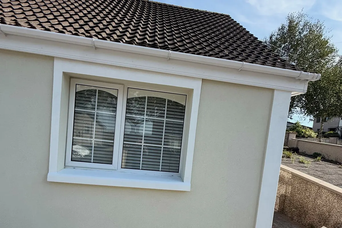 A finished window with a crisp white reveal band on cream render
